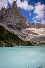 Obraz premium Photography of Lago di Sorapis, Italy, showing the turquoise glacial lake surrounded by Dolomite mountains, pine forests, and dramatic alpine scenery.
