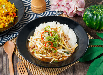 Stir fried pork with bamboo shoots and chili over rice in a rustic bowl side view of hong kong food