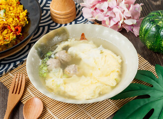 Egg Drop Soup with savory meatballs and fresh scallions in bowl side view of hong kong food