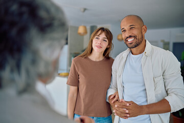 Young smiling couple listening to real estate agent explaining property details before buying new home