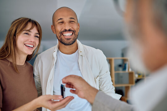 Realtor handing over house keys to joyful homeowners, celebrating the successful closing of their real estate deal and new journey ahead