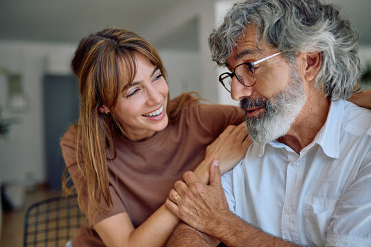 Smiling woman supporting senior man at home, holding hands and sharing a moment of affection and care - Powered by Adobe