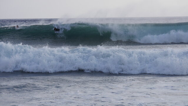 Man catching and surfing a wave during offshore conditions in Maui