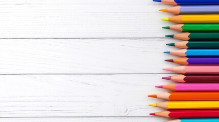 Obraz premium Colorful collection of pencils arranged neatly on a white wooden background, showcasing vibrant hues and artistic potential