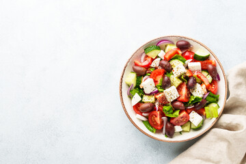 Greek salad in craft plate on white kitchen table.