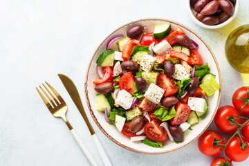 Greek salad in craft plate on white kitchen table.