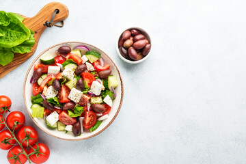 Greek salad in craft plate on white kitchen table.