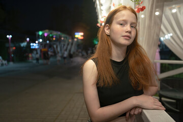 Teenage girl standing at railings in a park at night