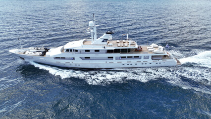 Aerial drone tracking photo of super yacht with wooden deck cruising deep blue Aegean Sea