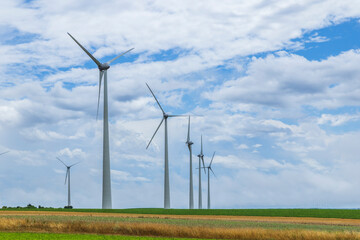 Wind turbines generating clean energy in cultivated fields under cloudy sky