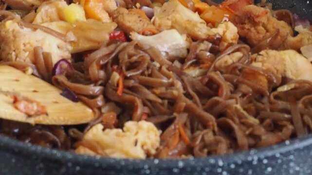 Schezwan Noodles or Vegetable Hakka Noodles or Chow Mein in white bowl. Schezwan Noodles is indo-chinese cuisine hot dish with udon noodles, vegetables and chilli sauce with meat, Japanese food