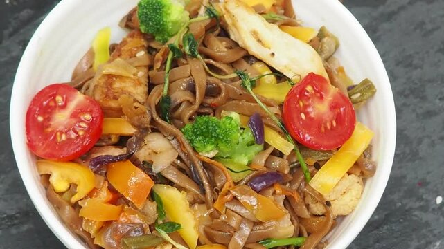 Schezwan Noodles or Vegetable Hakka Noodles or Chow Mein in white bowl. Schezwan Noodles is indo-chinese cuisine hot dish with udon noodles, vegetables and chilli sauce with meat, Japanese food