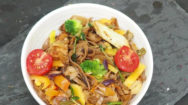 Schezwan Noodles or Vegetable Hakka Noodles or Chow Mein in white bowl. Schezwan Noodles is indo-chinese cuisine hot dish with udon noodles, vegetables and chilli sauce with meat, Japanese food
