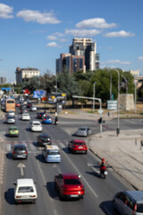 Obraz premium A blurry, high-angle view capturing cars and a red van in motion on a busy city road. The shot conveys the feeling of a typical daily commute in a bustling urban environment