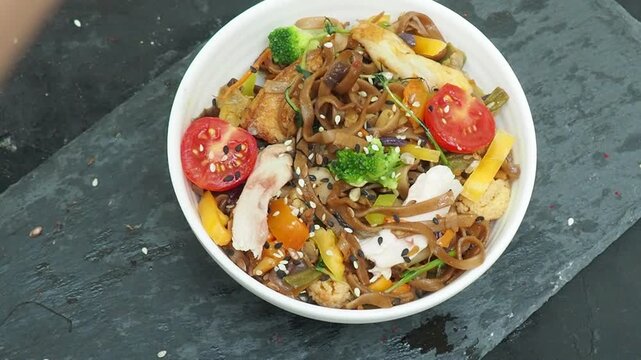 Schezwan Noodles or Vegetable Hakka Noodles or Chow Mein in white bowl. Schezwan Noodles is indo chinese cuisine hot dish with udon noodles, vegetables and chilli sauce with meat, Japanese food