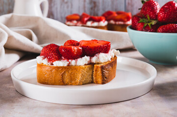Grilled toast with cream cheese and stewed strawberries on a plate on the table
