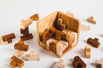 Wooden box half filled with puzzle pieces on light background
