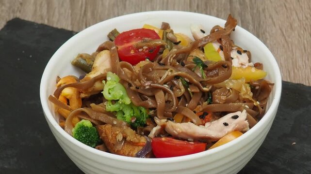 Schezwan Noodles or Vegetable Hakka Noodles or Chow Mein in white bowl. Schezwan Noodles is indo chinese cuisine hot dish with udon noodles, vegetables and chilli sauce with meat, Japanese food