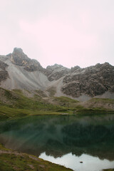Kristallklarer Bergsee vor steiler Felskulisse in den Alpen