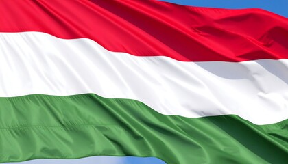 Fototapeta premium Hungarian flag billowing in the wind against a clear blue sky. Detailed close-up