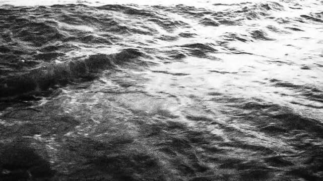 Gentle waves crash on sandy shore of Canj in Montenegro as the morning sun casts a soft glow. The tranquil Mediterranean landscape invites relaxation and peace. Black-white monochrome high contrast