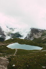 Hochalpiner Bergsee umgeben von dramatischer Felslandschaft und Nebelschwaden