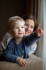 Naklejka premium Cheerful toddler pointing skyward as caring mother observes nearby, capturing tender family interaction within soft, inviting domestic setting