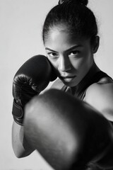 Muscular female boxer punching forward, black and white portrait highlighting athletic prowess, fierce determination, and powerful boxing technique