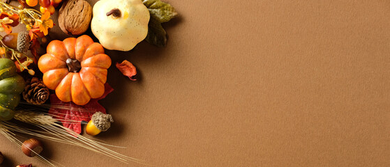 Rustic autumn banner design with pumpkin, gourd, nuts, leaves, and wheat on brown textured...