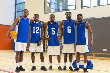 African american male basketball athletes in blue uniforms standing on court with basketball