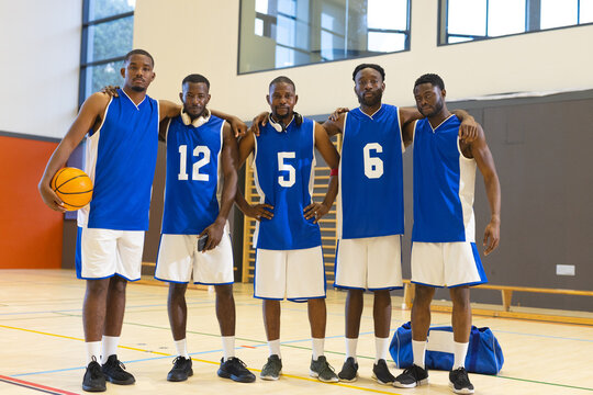 African american male basketball athletes in blue uniforms standing on court with basketball