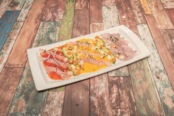 Plain tiradito with coconut tiger's milk and limo chili, presented over ice to maintain its freshness, with tender corn on the side