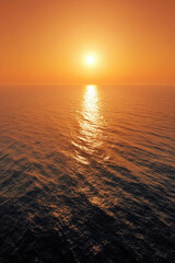 Obraz premium aerial view captures tranquil surface of ocean at sunset where water glistens with golden and orange hues