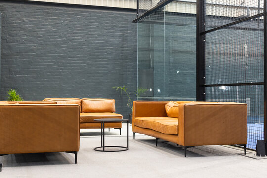 Displaying tan leather sofas facing each other around coffee table on carpet in office lounge