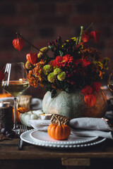 Fall composition. Orange pumpkins, flowers and candles on wooden table. Family elegant Thanksgiving or halloween dinner. Cozy autumn concept, simple handmade decoration, countryside style, wine