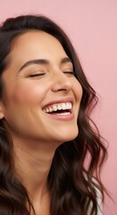 A smiling woman with closed eyes reveals her perfect white teeth on a pink background.