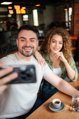 Couple taking a selfie while having coffee in a cafe