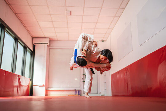 Two martial arts athletes performing judo throw in gym