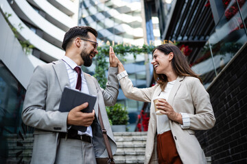 Business people giving high five outdoors in urban city celebrating success