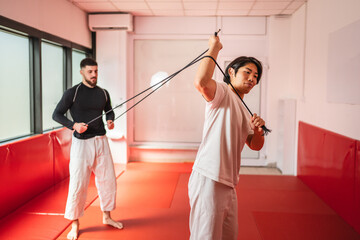 Two martial arts athletes training with resistance band in gym