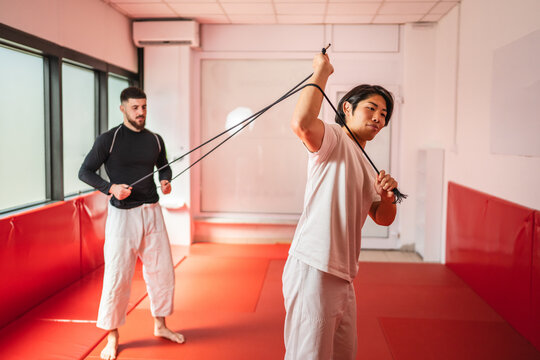 Two martial arts athletes training with resistance band in gym