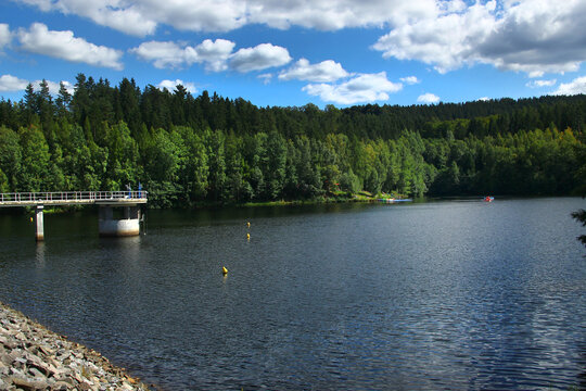 Scenic View of Talsperre Falkenstein Reservoir with Forested Hills and Blue Sky, located in Saxony, Germany