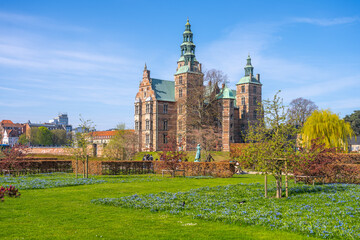 Obraz premium Rosenborg Castle in Copenhagen is surrounded by vibrant gardens and blooming flowers, showcasing Renaissance architecture against a clear blue sky in the joy of spring.