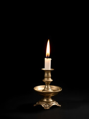 burning old candle vintage Silver bronze candlestick. Isolated Black Background.
