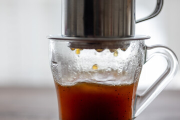 Brewing Elegance: Metal Dripper Pouring Rich Coffee into a Glass