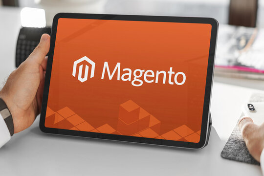 Businessman holding tablet displaying magento logo in office setting