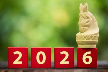 New Year of the horse and 2026 on the logs and old cream-colored knight horse on natural background.