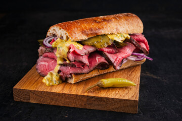 Traditional sliced cold cuts roast beef sandwich with onion, gherkin and onion served as close-up...