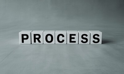 White cubes spell out the word "PROCESS" on a neutral gray background