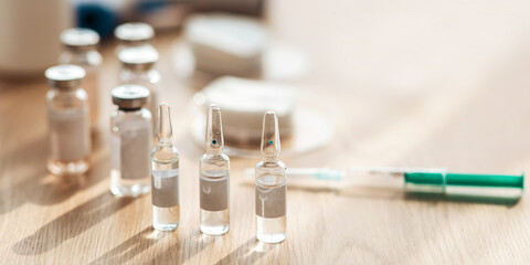 Medicine, pharmacy and health care, vaccination and treatment. Ampoules with vaccine, medicines, syringe with needle, cotton pads on table for injection in clinic, free space, panorama, close up